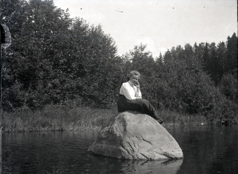 Женщина, сидящая на камне у реки